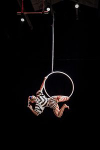 caucasian woman hanging on a hoop that is connected to a rope on the ceiling