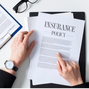 caucasian hands pointing at a piece of paper that says "insurance policy" on it