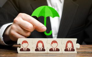 torso of a person with a suit in holding a green umbrella over blocks with peoples silhouettes on them