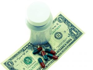 pill bottle sitting on top of a dollar bill with pills on the bill too
