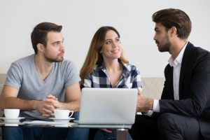 caucasian man and woman sitting with a cauasian man with a suit on