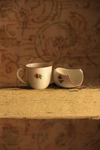 two cups on a table, one of them broken.