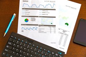 two pages with data reports on them laying on a table next to a computer keyboard