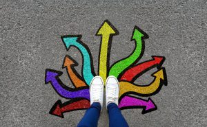 persons legs with white sneakers on in the middle of many different colored arrows around the feet pointing in different directions.