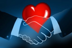 two hands shaking with a red heart in the background