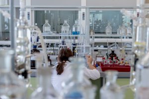 back of a woman with her hair in a ponytail in a lab testing something