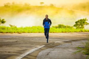 african american man with a jogging suit on running on the road