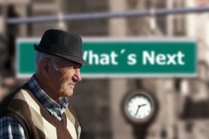 older caucasian man with a green sign behind him that says "what's next"