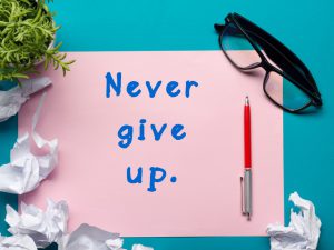 never give up on a pink piece of paper and a red pen next to the words.