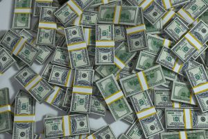 piles of hundred dollar bills strapped together by a band laying on top of each other