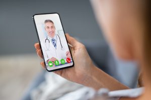 person holding a cell phone with a caucasian male doctor on the screen