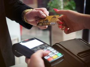 caucasian hand handing another hand a gold credit card