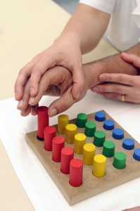 caucasian hand over an older caucasian hand bringing it towards blocks