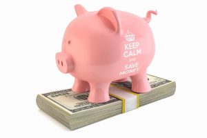 pink piggy bank standing on top of some money