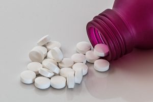 purple pill bottle laying down with white circle pills poured out
