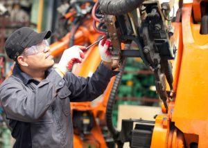 caucasian man working on a large machine with a screwdriver
