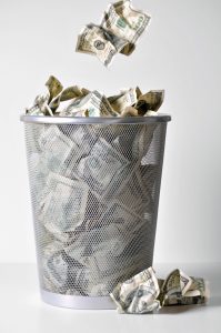 hundred dollar bills and other bills crumbled in a trash can