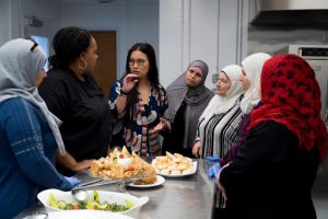 Jin-Ya Huang standing around a table with food on it and women with hijabs on