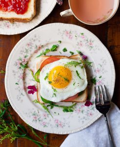 dish with an egg on toast and a cup of tea next to it on the table