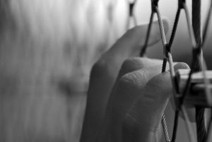 black and white picture of a hand on a fence.