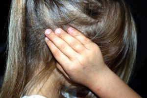 young caucasian girl holding her hear with her hand