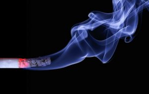 cigarette lit with ashes flowing from it