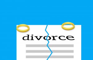 two rings on the ends of a paper with the word divorce on the paper and a rip in the middle
