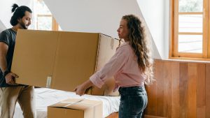 man and woman moving a heavy cardboard box together