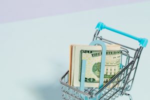 shopping cart with money held in a paperclip inside of it.