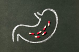 drawing of intestine on a blackboard with red and white pills inside of the drawing