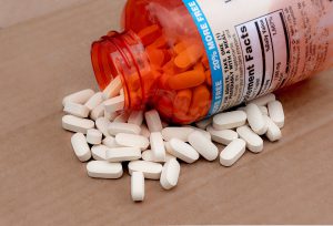 orange pill bottle laying on a table with long white pills spilling out of it