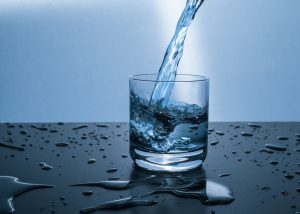 glass of water being poured with water around the cup on the table