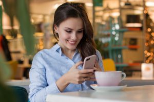 caucasian woman looking at her cell phone screen while smiling