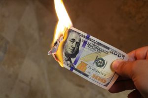 a hundred dollar bill on fire, burning.
