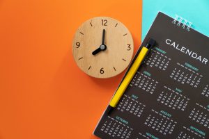 a clock with a black calendar next to it with an orange background