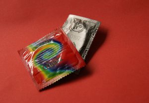 a colorfully wrapped condom wrapper with a little silver pouch next to it