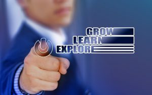 person in a suit pressing a button with the words "grow, learn, explore" next to it