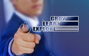 person in  a suit pressing a button with the words "grow, learn, explore" next to it
