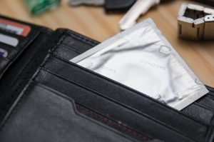a silver packaged condom in a black wallet