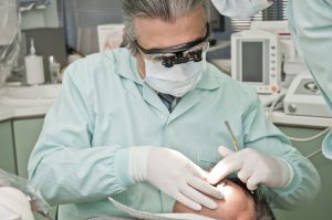 male caucasian dentist looking in the mouth of a patient