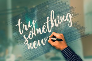 try something new written in white by a caucasian hand with a blue background