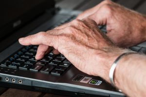 elderly caucasian hands typing on a keyboard.