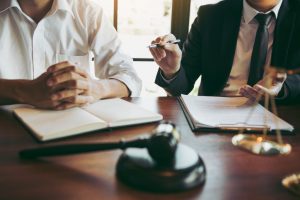 two people sitting in a room with files and a gavel in front of them