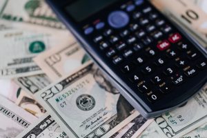 black calculator on top of different amounts of money bills.
