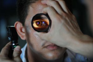 man with a magnified glass in front of his eye