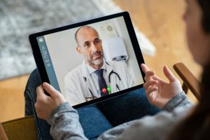 doctor on a screen with caucsian hands holding it up