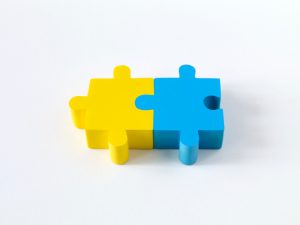 two puzzle pieces together, one yellow and one light blue