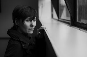black and white picture of a caucasian woman looking out a window