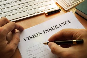 vision insurance on a paper with a hand with a pen in it about to fill it out