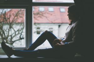 woman sitting on a window sill looking outside